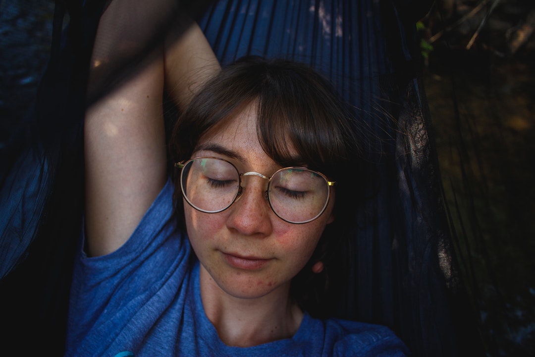 Woman in retro circle glasses closing her eyes and relaxing