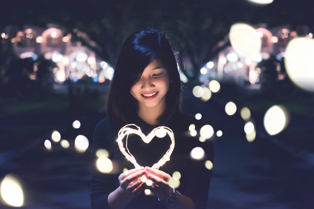 woman holding lit heart