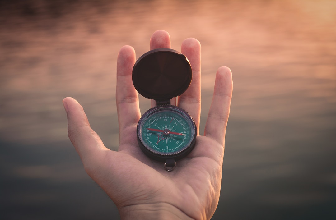 A compass is held in a man's left hand.