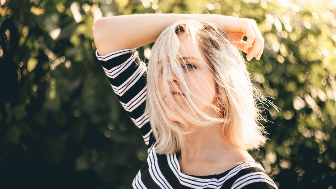 Woman with wind in her hair posing in a striped shirt