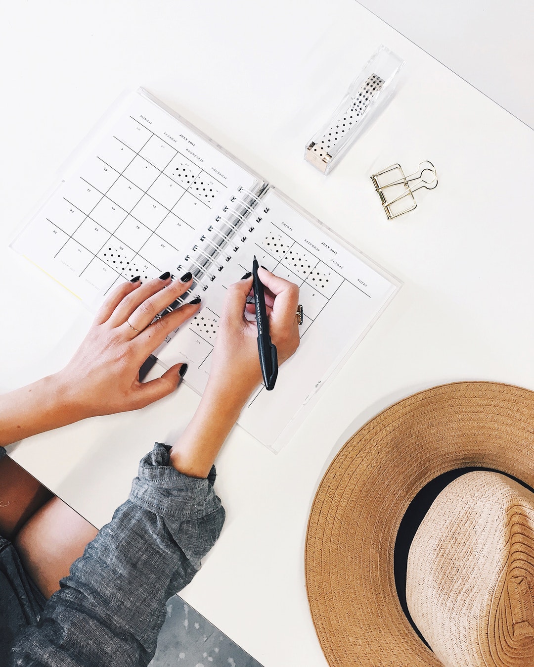 An overhead shot of a person writing in a planner on a desk