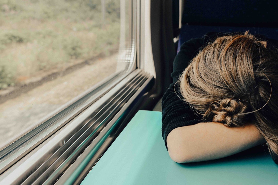 Tired woman with her head down on a train tray table
