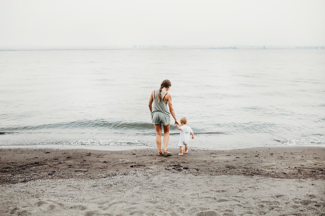 A mother and daughter walking down the beach near the water in Wintler Community Park