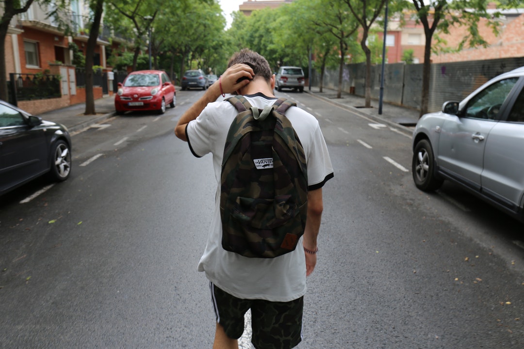 Teen boy walking home from school wearing a backpack