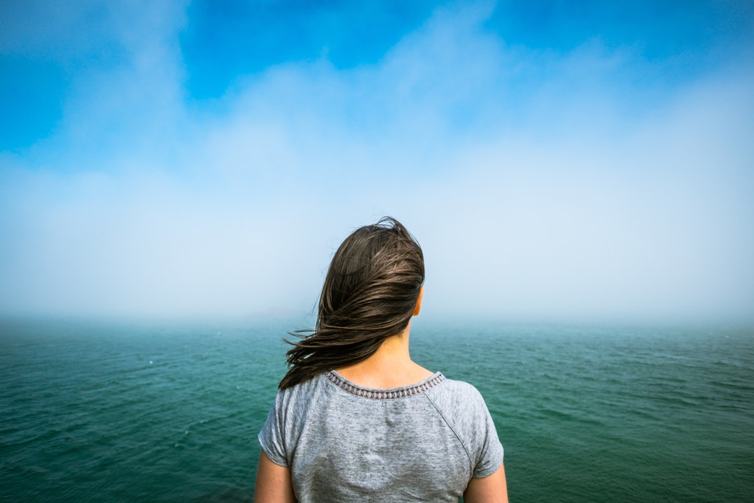 woman looks out at windy ocean view