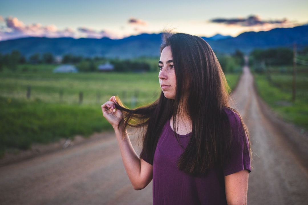 Woman playing with her hair standing on a farm road