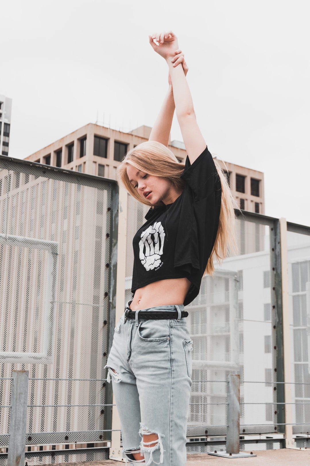 Woman in ripped jeans and a skull shirt stretches her arms