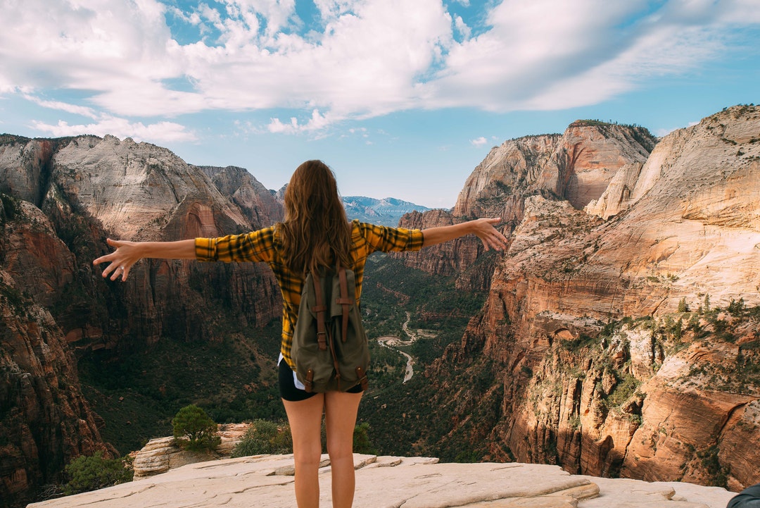A woman with her arms spread out on top of a mountain.