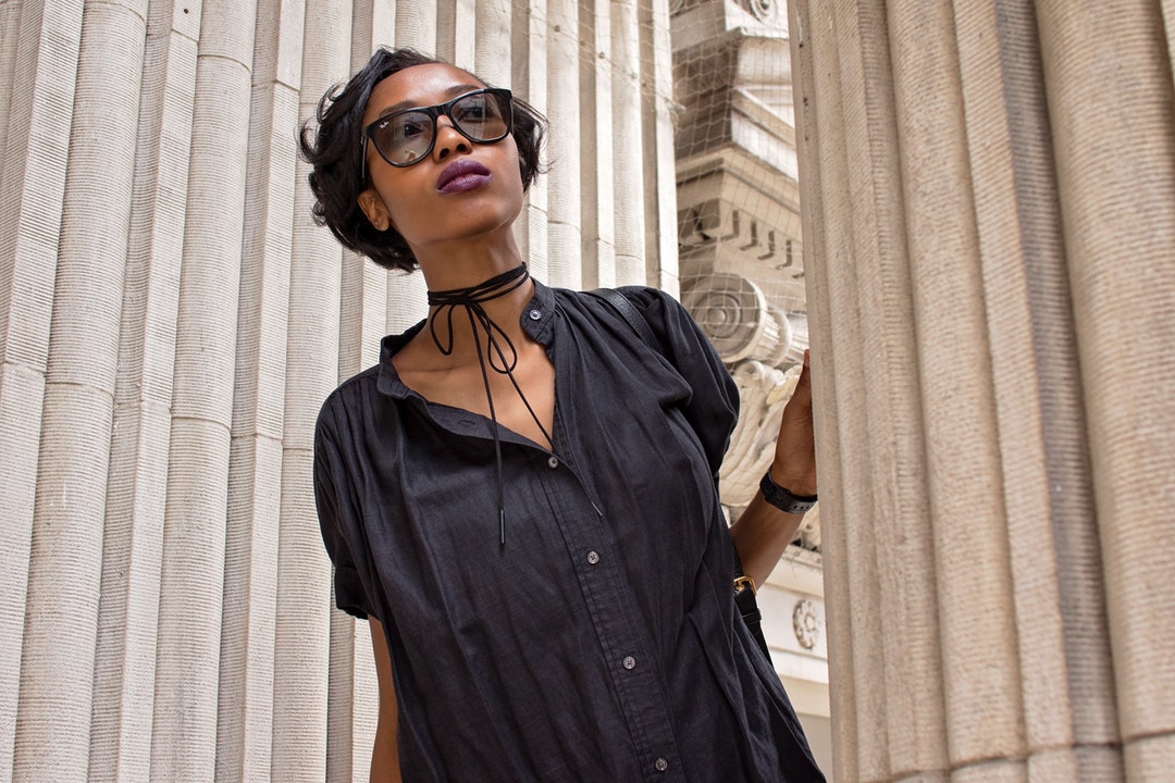 woman standing beside concrete pillar during daytime