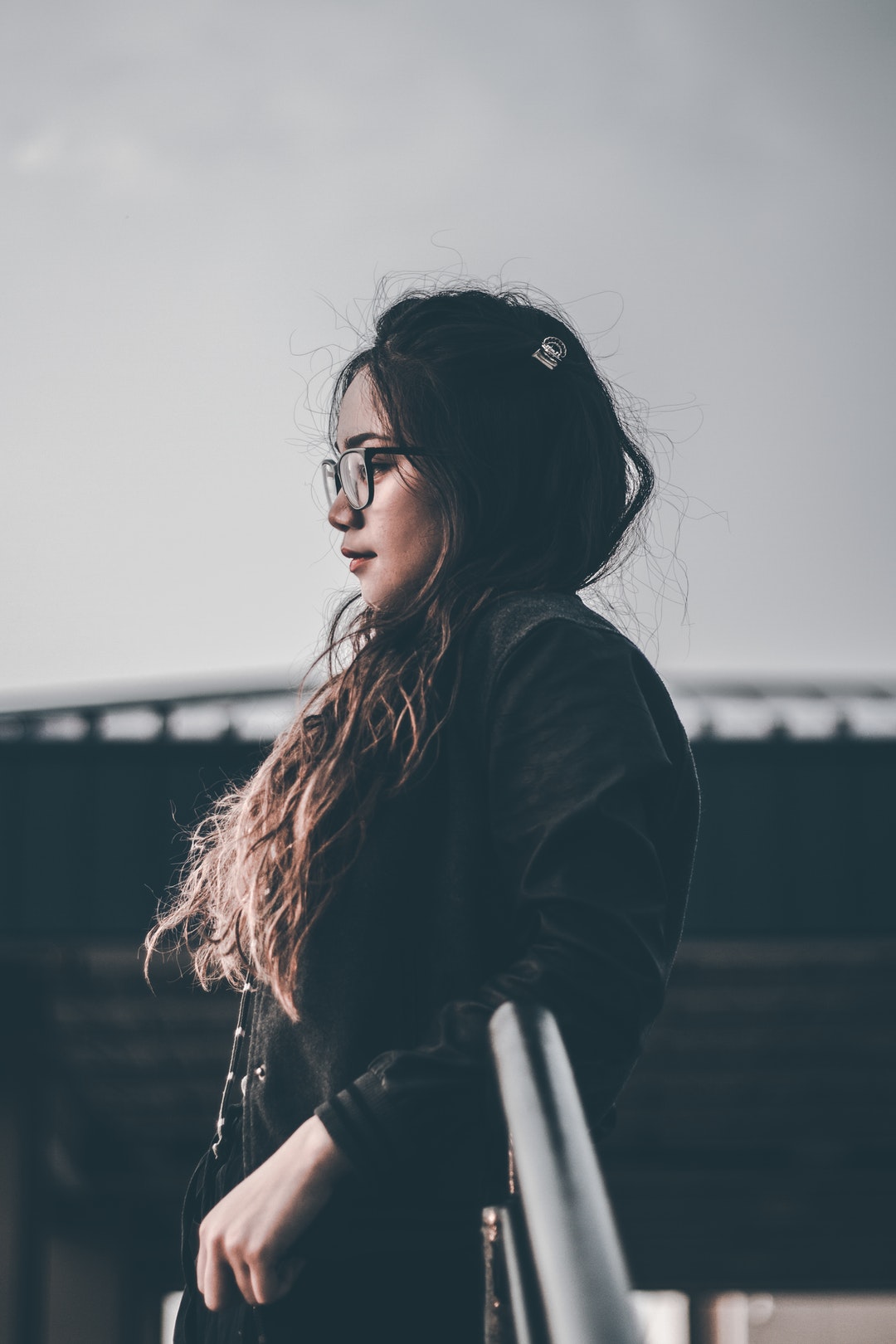 selective focus photography of woman standing beside railing