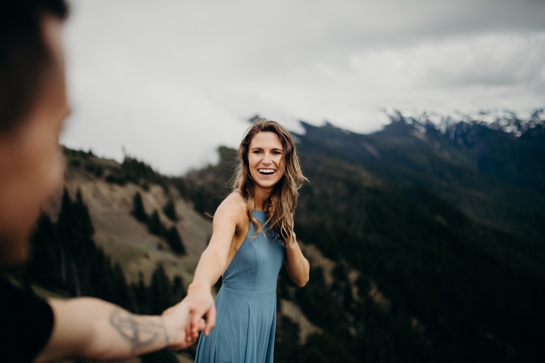 woman holding man's hand while smiling
