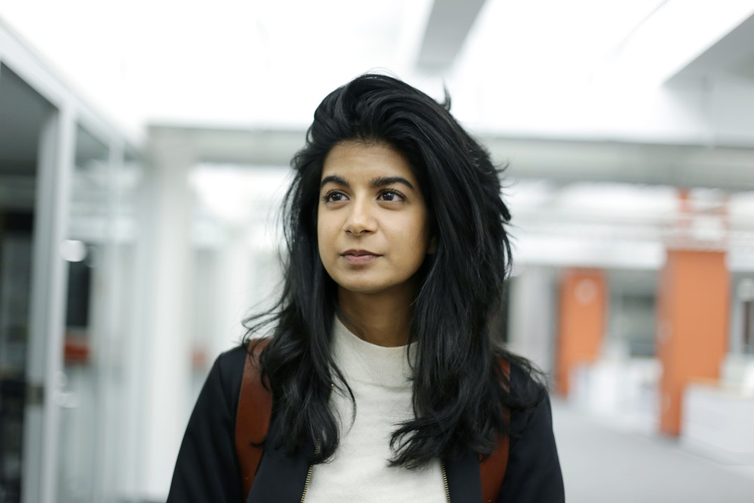 portrait photography of woman standing beside glass door