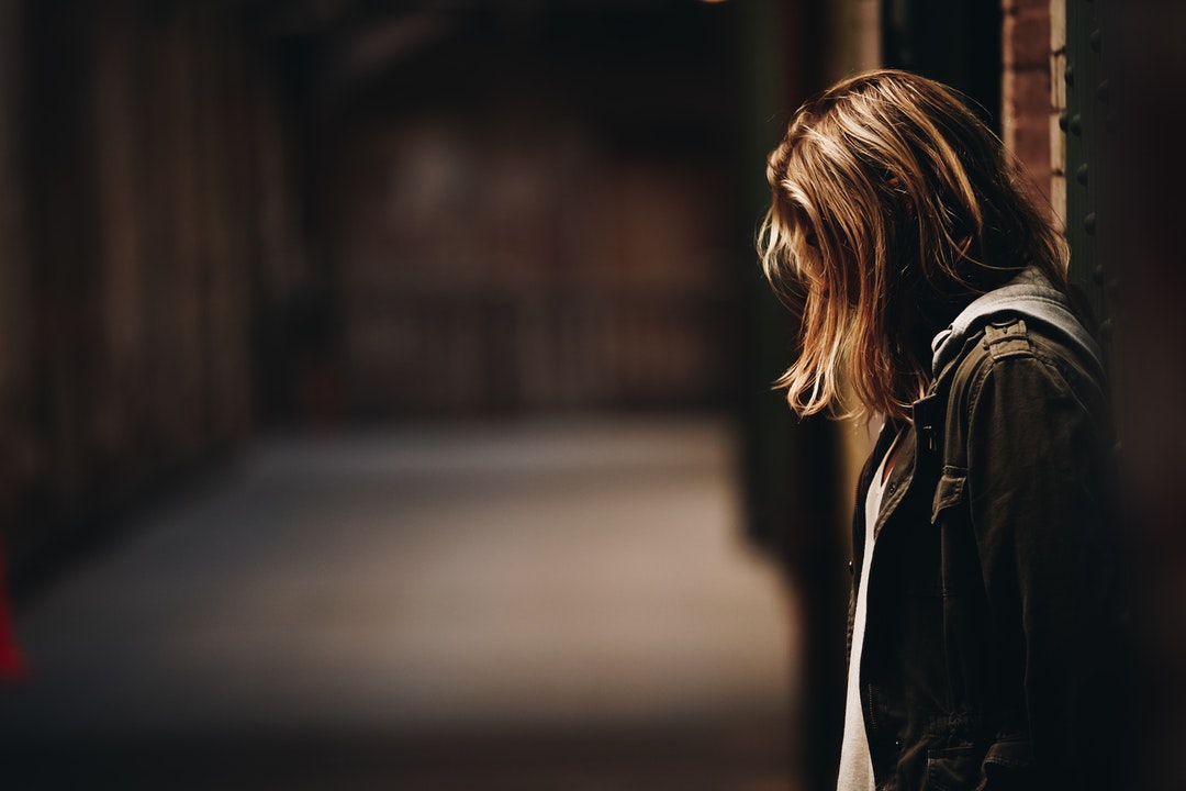 woman leaning against wall facing down
