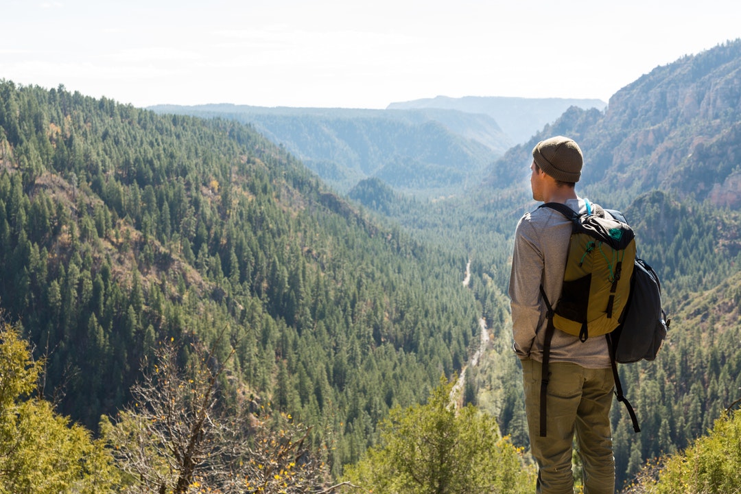 man standing on cliff near mountains