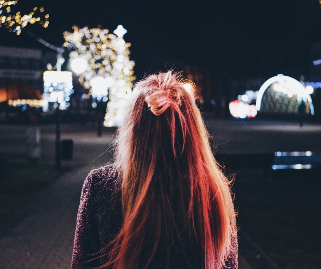 woman facing tree with lights during night time