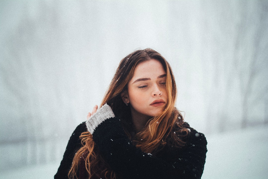 woman wearing black coat holding her hair