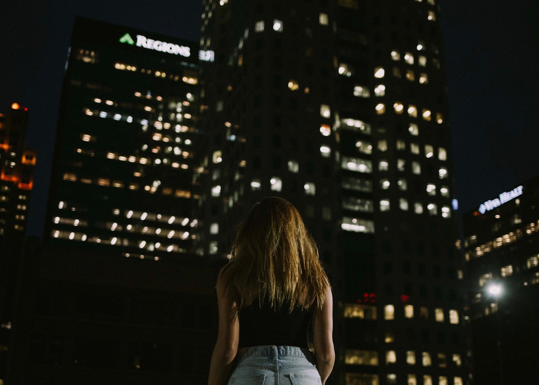 woman stands in front of high-rise buildings