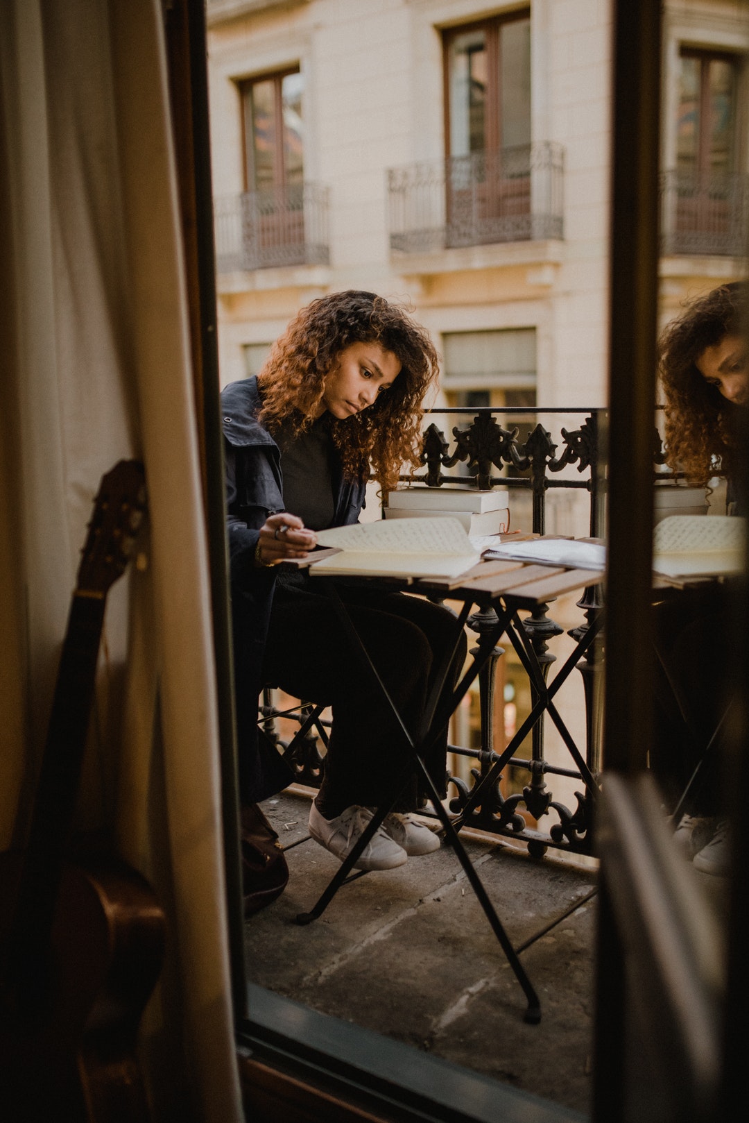 woman sitting on chair beside railings reading book