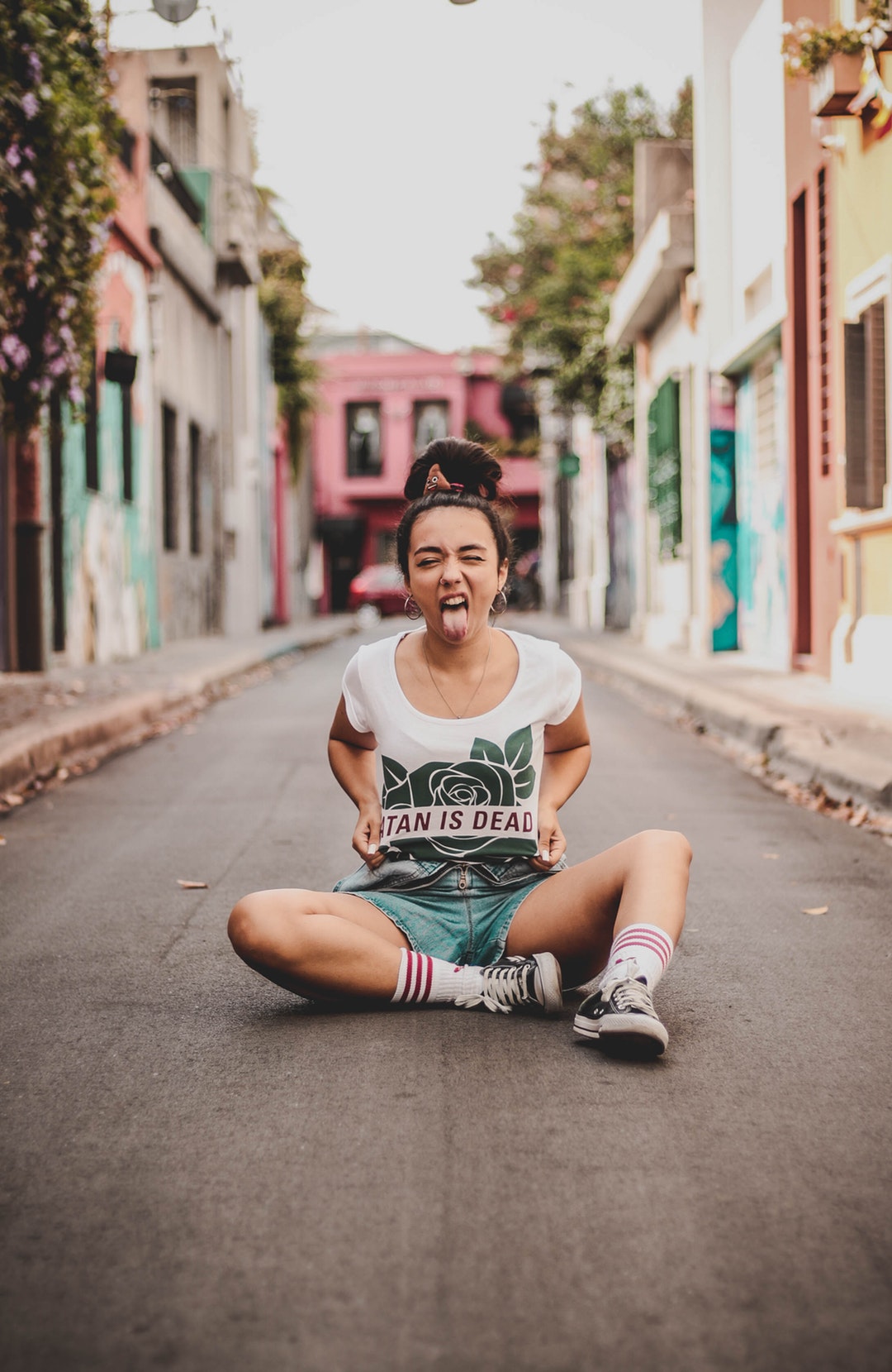 woman sitting on road with pair of shoes at daytime