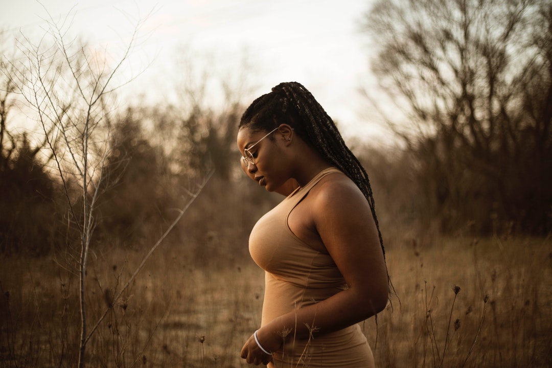 woman wearing brown tank top standing near grass