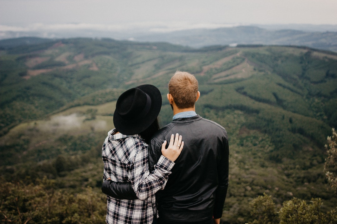shallow focus photography of man and woman looking down from mountain