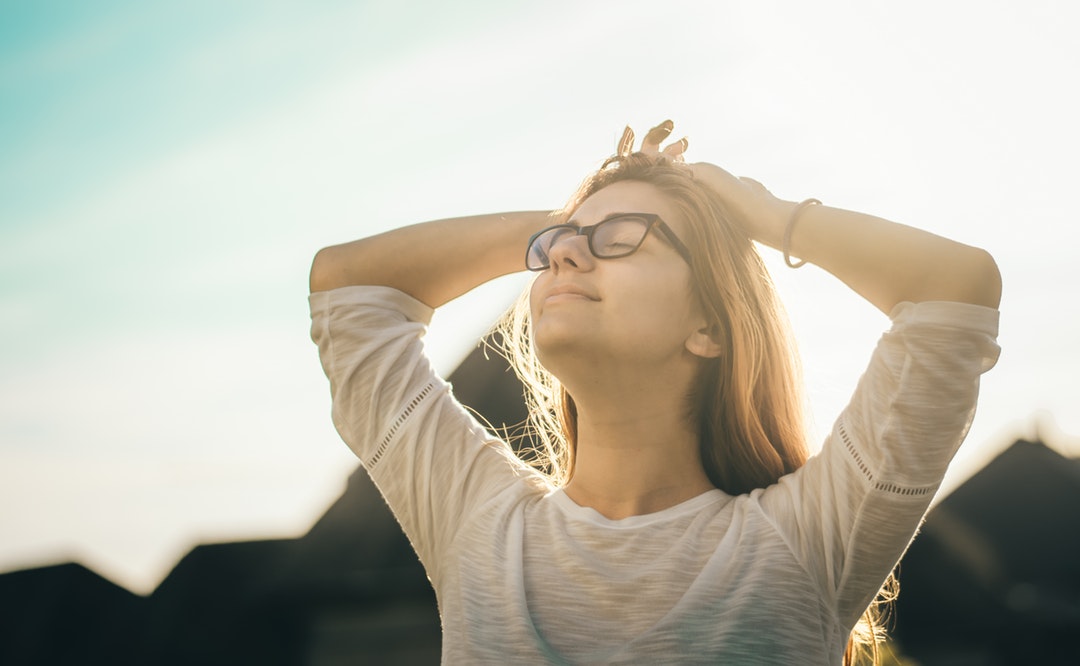 woman in white crew-neck T-shirt holding her head