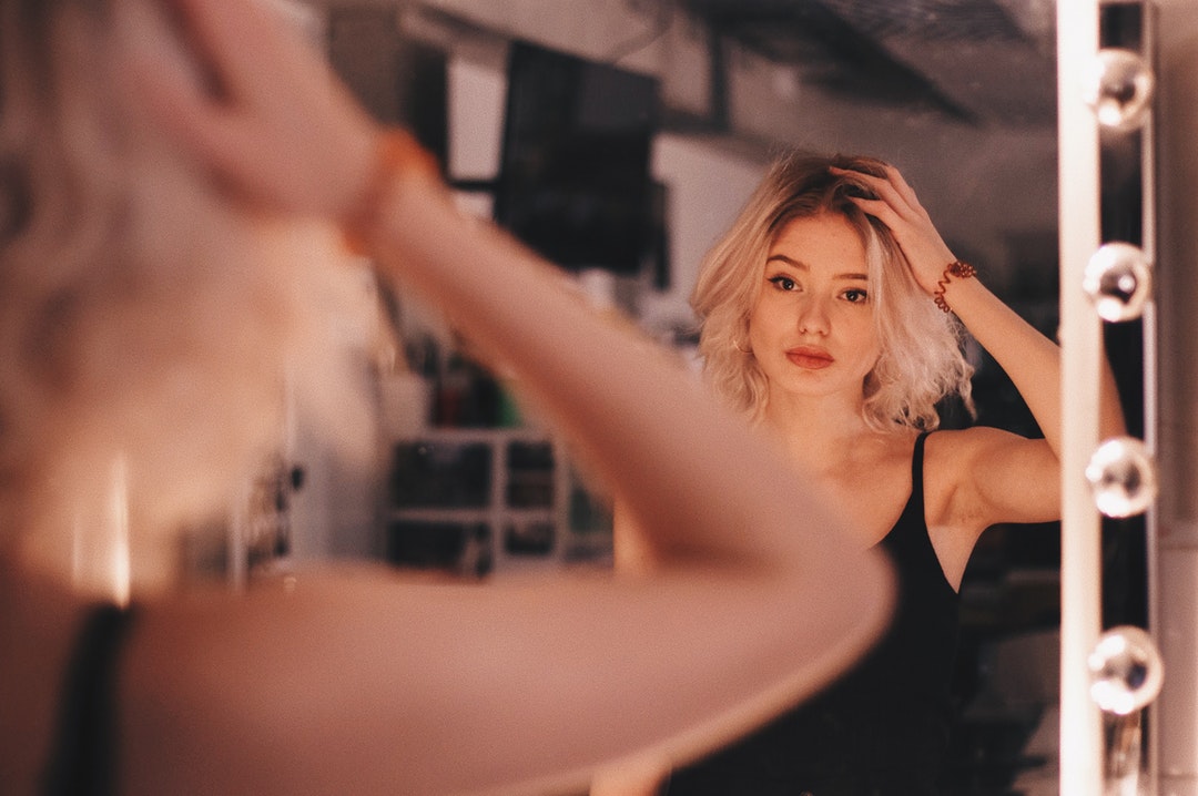 woman touching her hair in front of mirror