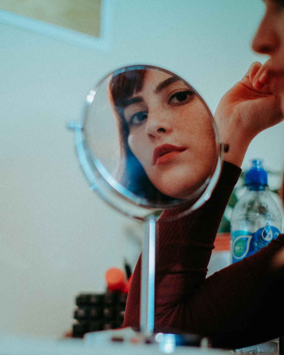 woman staring at round mirror with silver frame