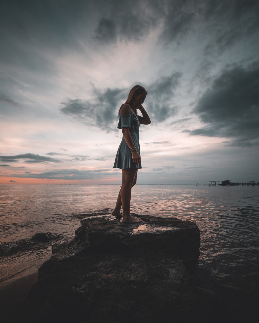 woman standing on rock near body of water