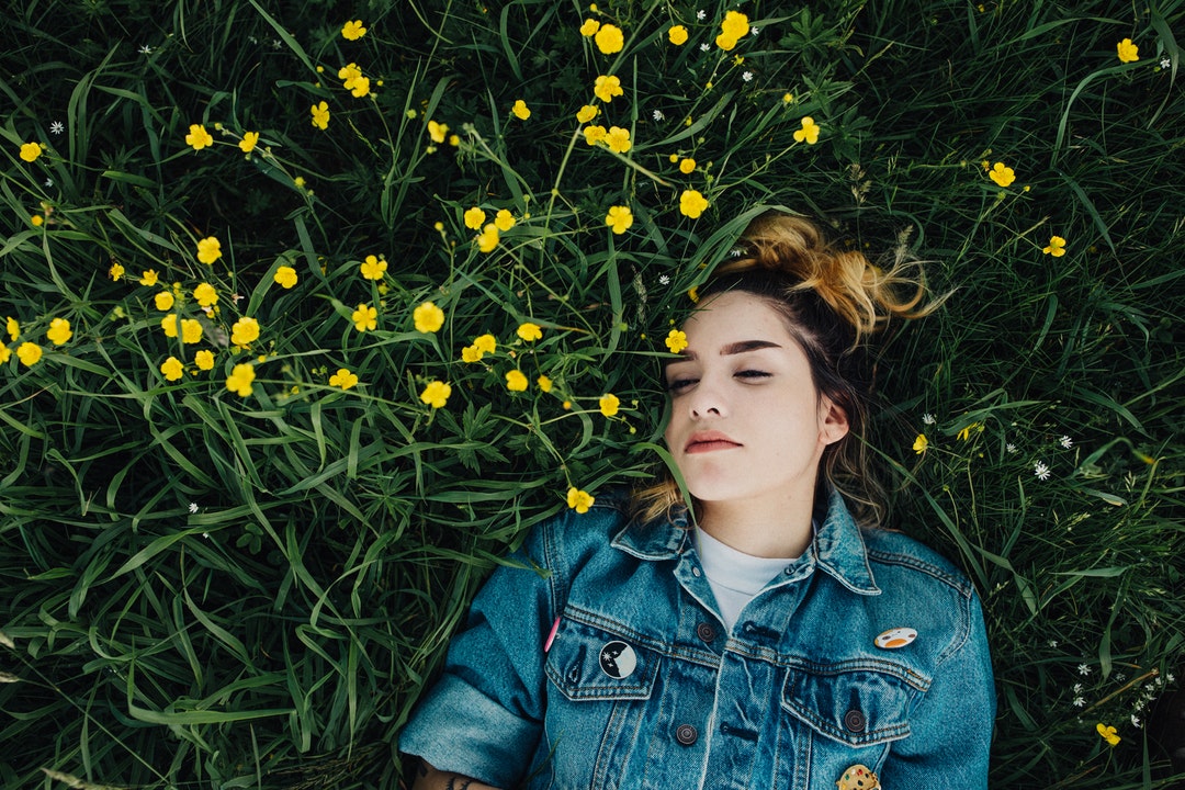 woman in blue chambray jacket lying on green grass