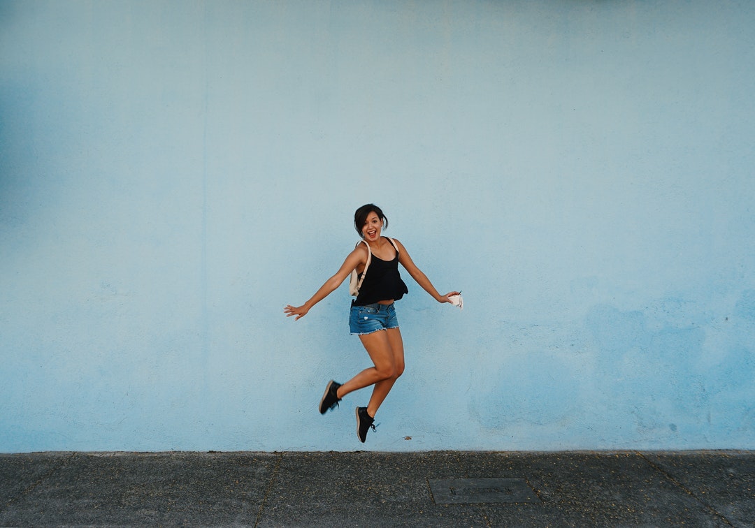 jumping woman on gray ground under white cloud blue skies