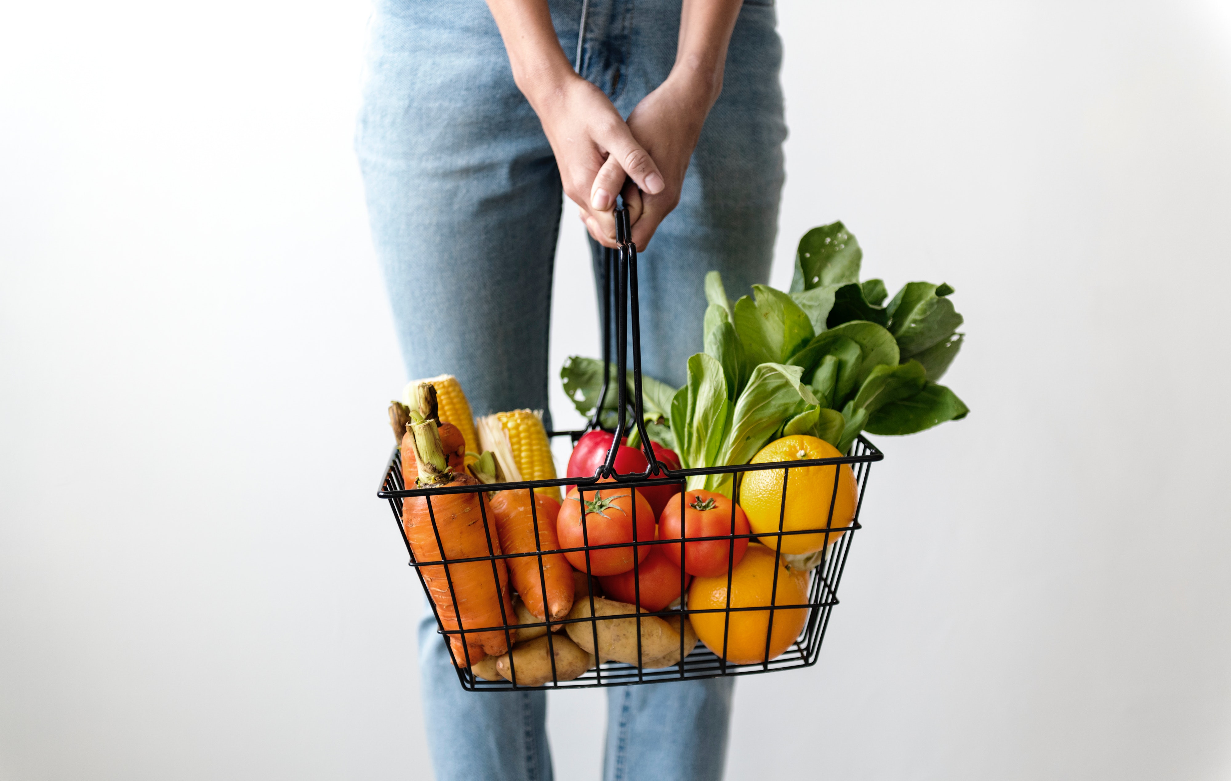 person holding basket filled with vegetables