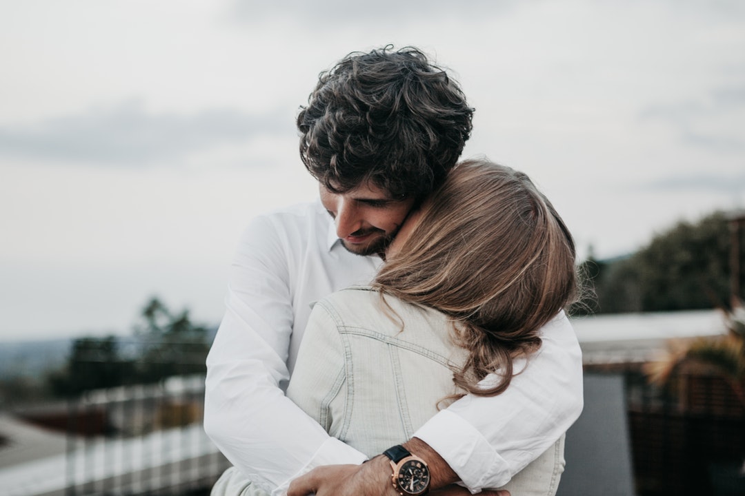 woman kissing man on neck