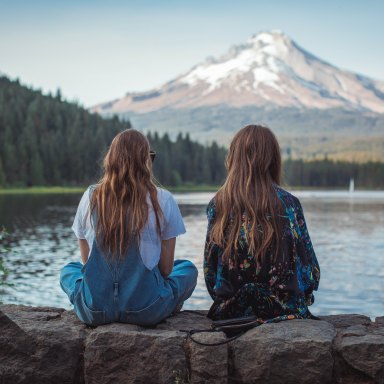 two girls sitting staring at a mountain