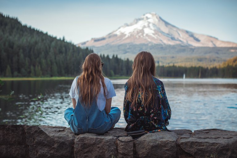 two girls sitting staring at a mountain