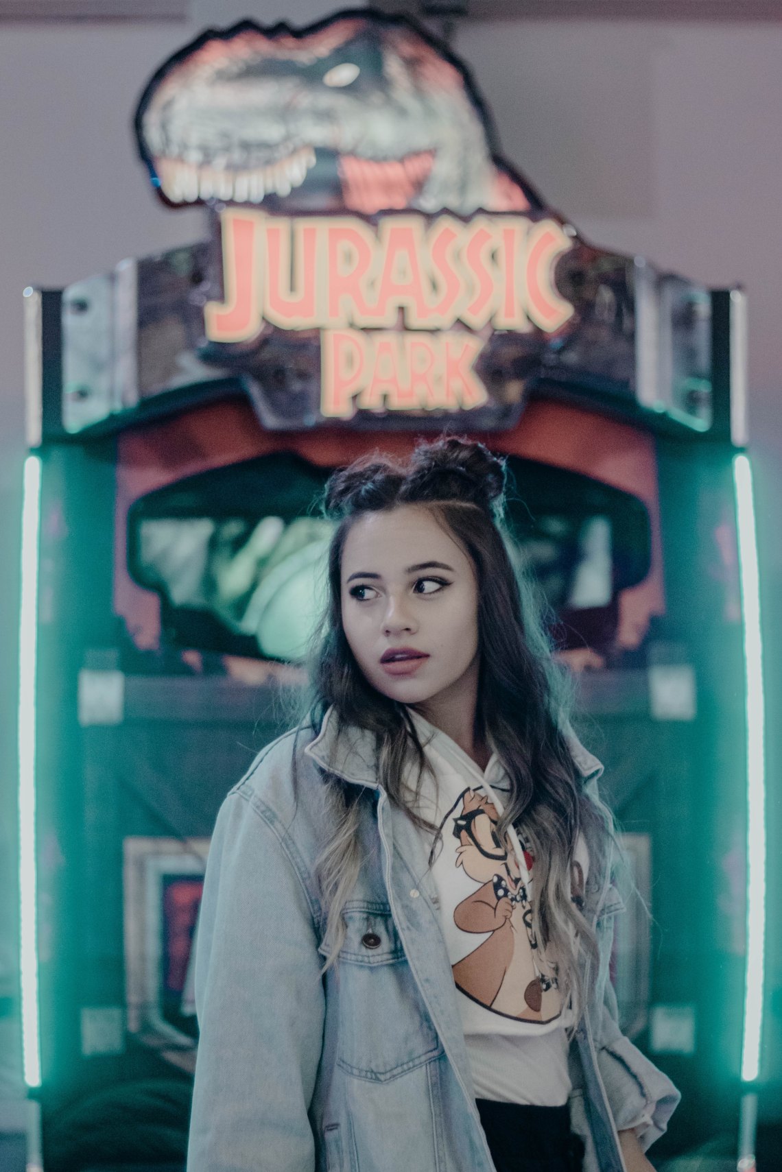 girl standing in front of a jurassic park sign 
