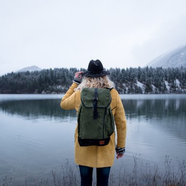 girl backpack lake hat trees