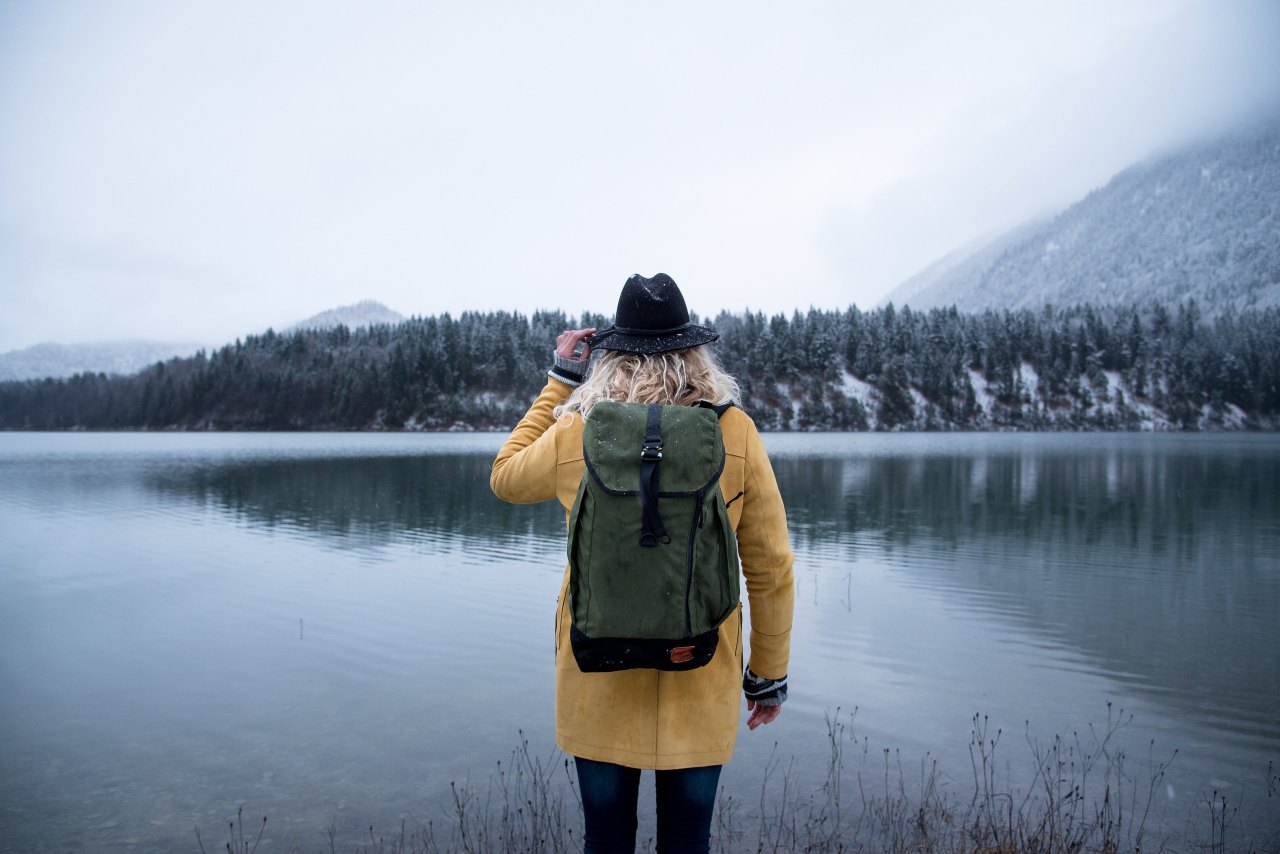 girl backpack lake hat trees