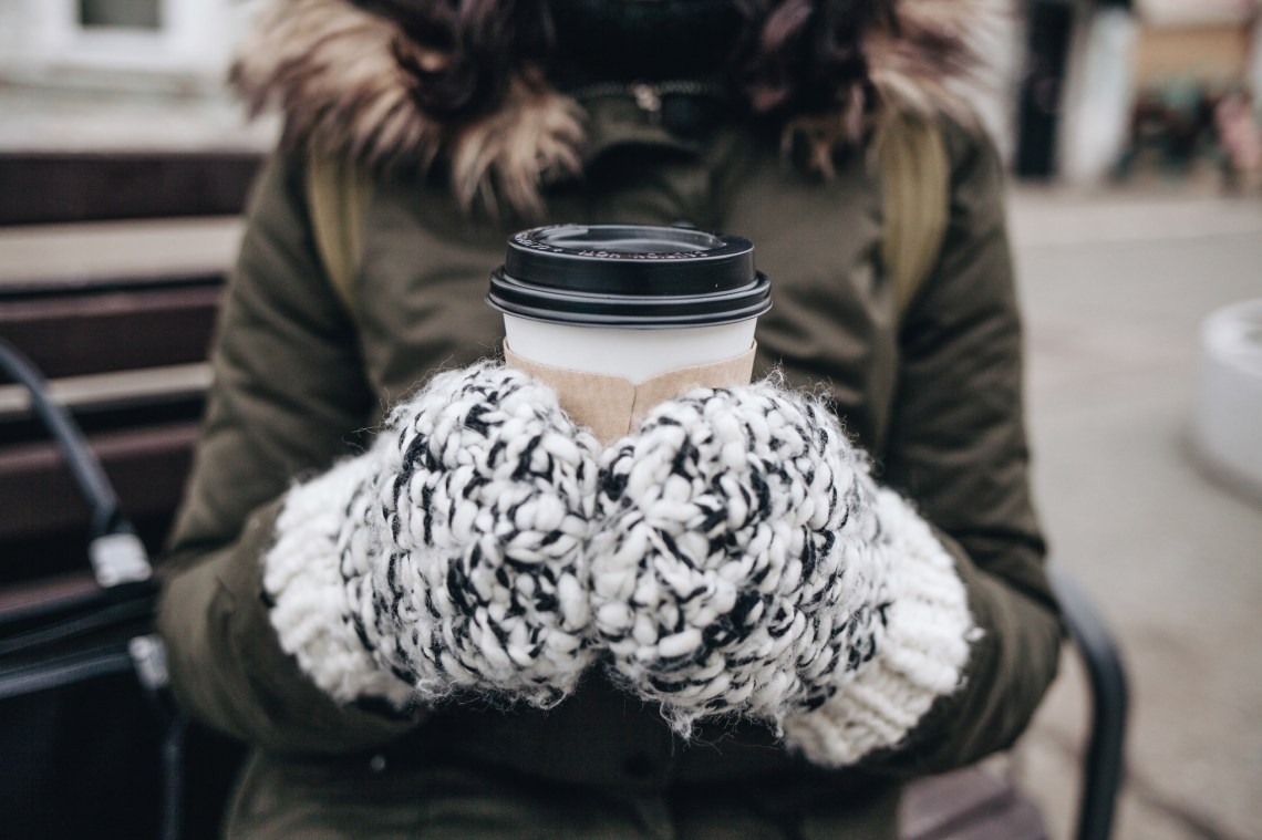 girl holding coffee in winter with gloves on and winter coat