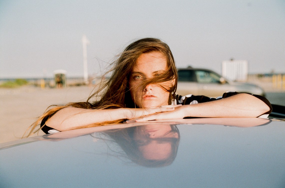 woman resting on top of car