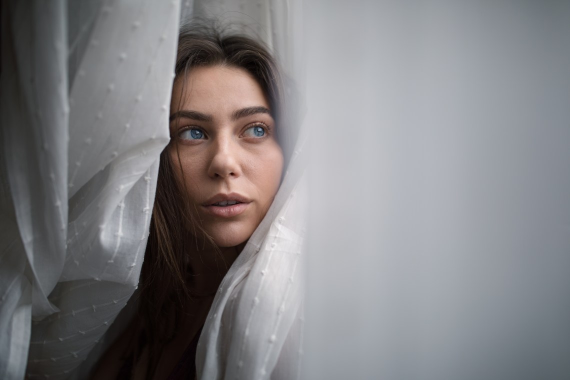 woman looking thoughtful in curtains