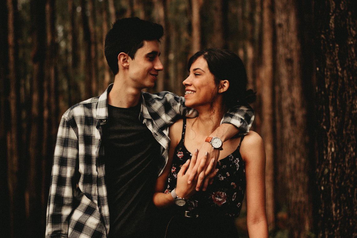 couple standing in woods looking happy