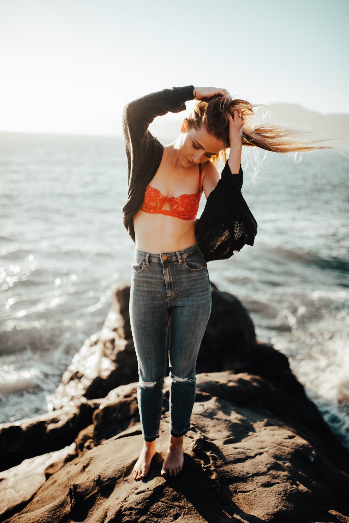 woman standing on rock in front of ocean