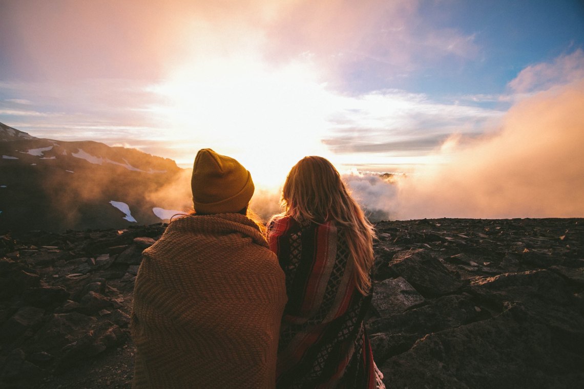 couple sitting on cliff, happy couple, apology language, apologies, love, zodiac sign