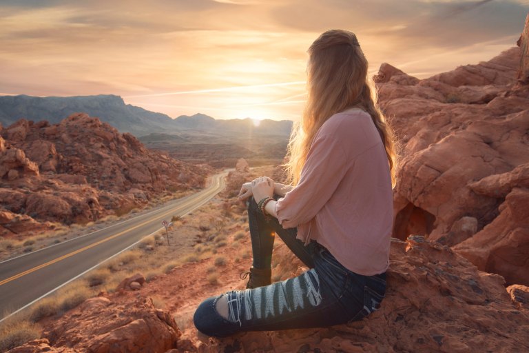woman sitting on rocks at sunset
