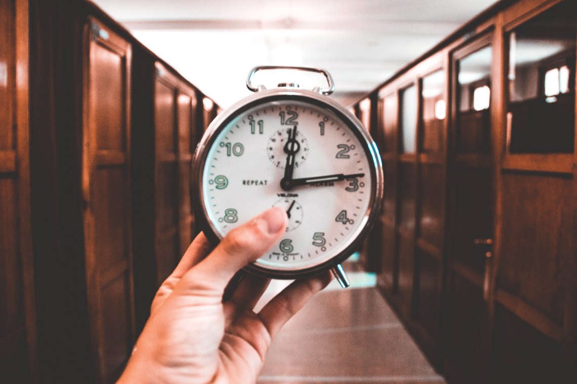 Someone holding up a clock in a hallway