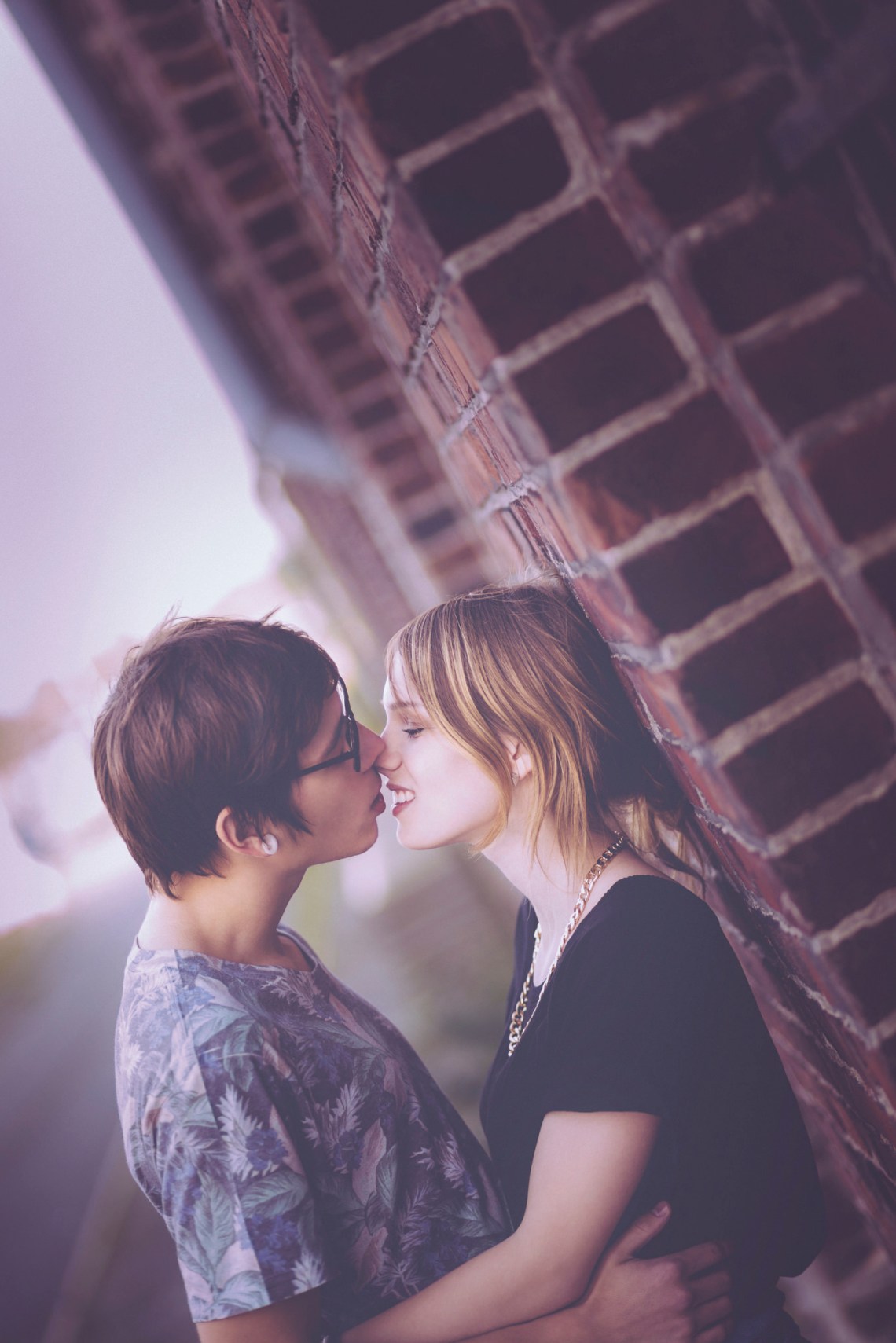 couple kissing near a brick wall