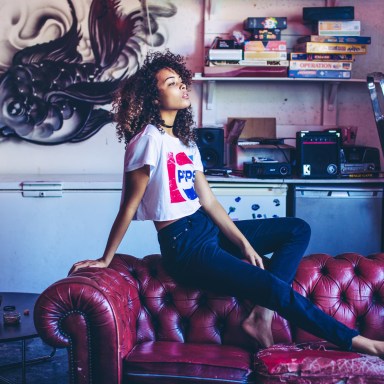 Young woman in Pepsi cropped tee t-shirt sitting on red leather couch, vintage board games