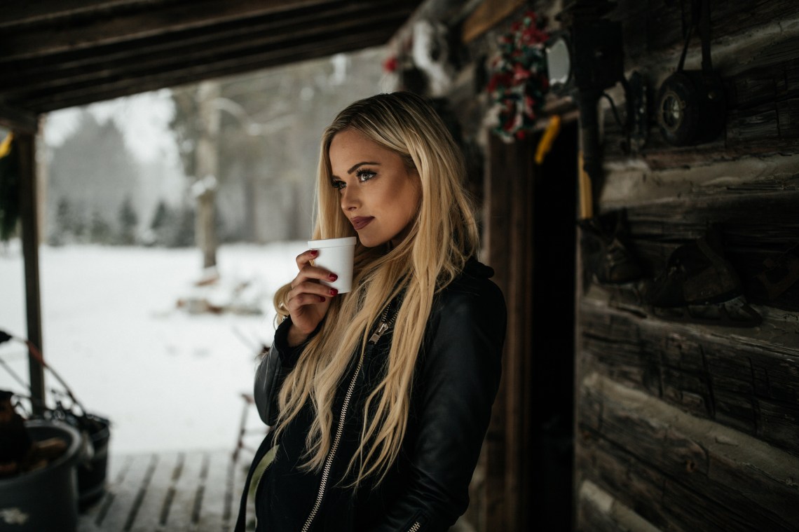 Blonde woman thinks about her life in winter while drinking a warm beverage