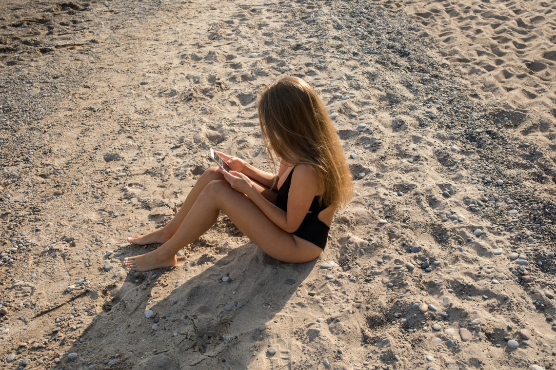girl texting on the beach